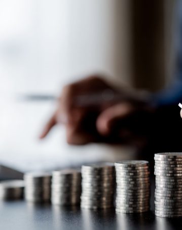 business-man-putting-a-coin-on-a-pile-of-coins-2025-01-16-22-01-48-utc